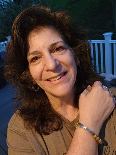 Reviewer smiling and showing her 'I CAN DO ALL THINGS THROUGH CHRIST' beaded bracelet on her wrist.