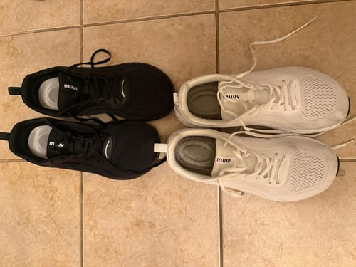Reviewer's two pairs of Flow Pickleball Shoes, one black and one white, laid out on a tile floor.