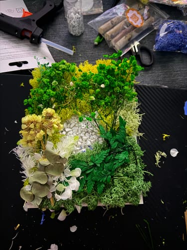Reviewer's vibrant moss art project made from This Month's Craft Subscription Box, with supplies in the background.