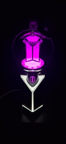 Customer's BTS Official Light Stick Ver.4 glowing with a bright purple light in a dark room.