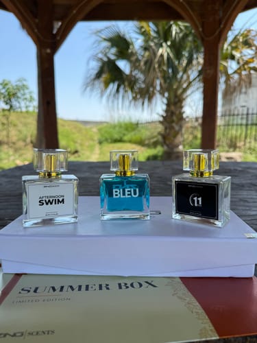 Customer's three fragrance bottles from a summer collection, displayed on a box outdoors.