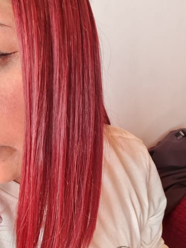 Clienta mostrando su cabello teñido de rojo, liso y sin frizz tras usar el Shampoo Antifrizz.