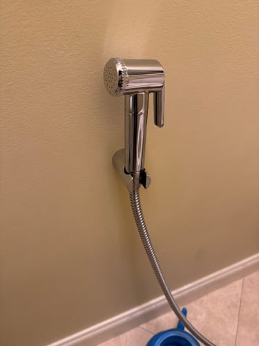 Customer's chrome Handheld Bidet installed and resting in its holder on a bathroom wall.