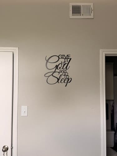 Customer's 'Give It to God and Go to Sleep' metal wall decor mounted on a light-colored wall in a room.