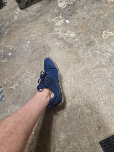Customer wearing a blue Wish Ⅰ - Barefoot Shoe on their left foot against a concrete floor.