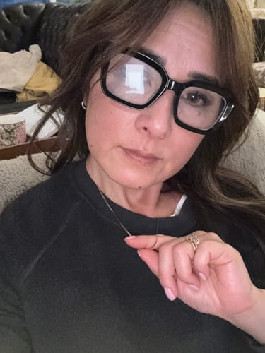 Reviewer wearing the thin, gold Fine Essentials Necklace against a dark sweatshirt.