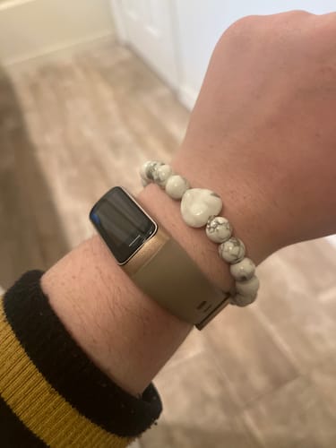 Customer wearing their howlite bracelet with a heart-shaped stone on their wrist next to a watch.