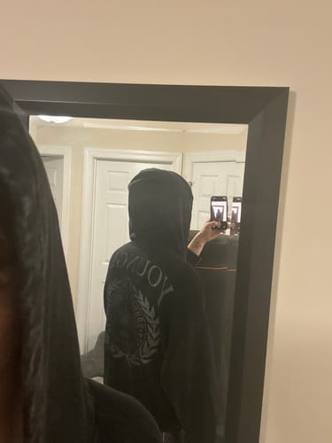 Reviewer wearing a dark Star Crest Zip-Up hoodie, showing the crest graphic on the back in a mirror.