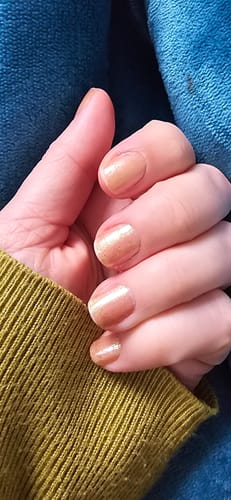 Nahaufnahme der Hand einer Kundin mit den durchscheinenden, sandfarbenen Emerald Sand Nagelfolien.
