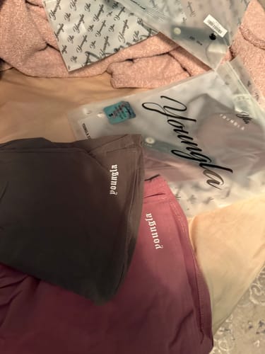 Customer's haul of YoungLA clothing, showing a folded dark grey skirt and a maroon skirt next to their packaging.