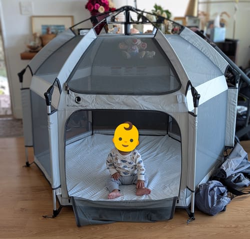 Reviewer's spacious Pop 'N Go LUXE Playpen set up indoors with a baby sitting comfortably inside.