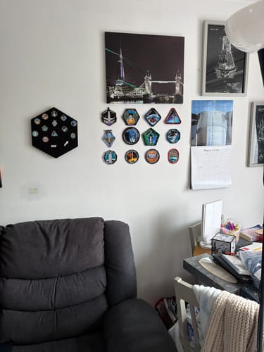 Customer's black, hexagonal SpaceX Pin Display Mount mounted on a wall next to other pictures in a room.