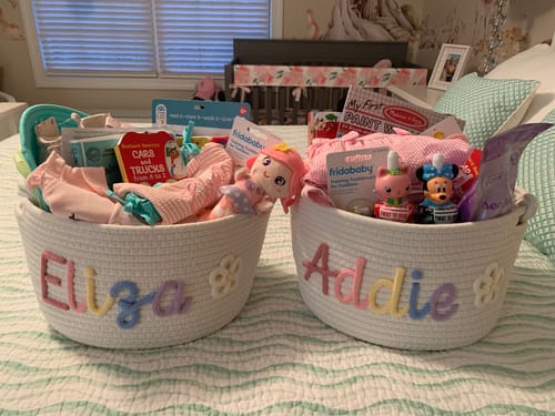 Customer's two personalized knitted baskets with names 'Eliza' and 'Addie' in multicolor yarn, filled with Easter gifts.