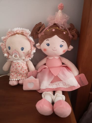 Customer's soft Personalized Cherry Baby Girl doll sitting on a wooden dresser next to another pink doll from their collection.