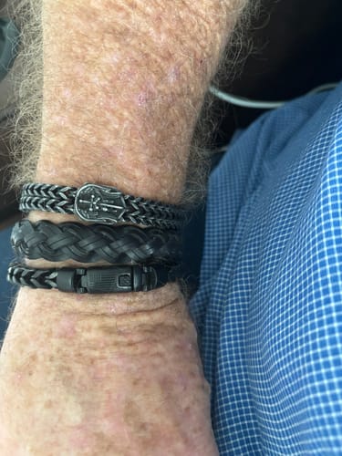Close-up of a reviewer's wrist wearing the snug, black Black Mamba Bracelet with other bands.