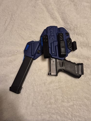 Customer's blue MSP PRO SERIES FLX holster holding a pistol and an extended magazine on a fluffy white surface.