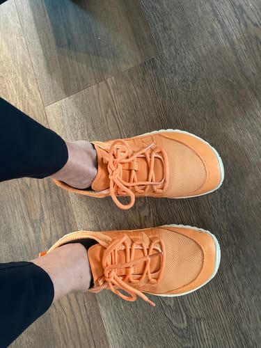 Customer's overhead view of the orange Forestep Ⅰ - Barefoot Shoes on their feet against a wood floor.
