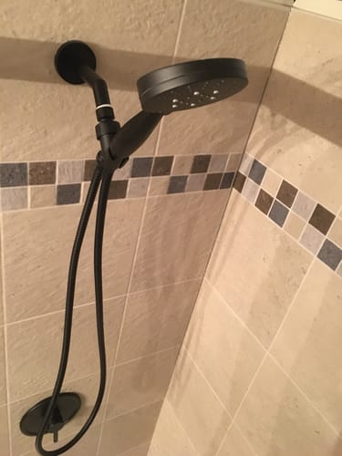Customer's new black handheld shower head and system installed in a tiled shower.