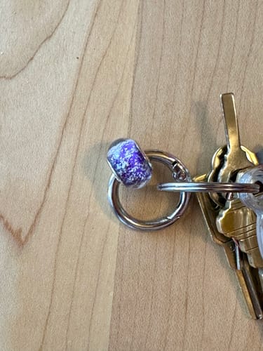 Customer's plum Solid Color Bead with Cremains attached to a key ring.