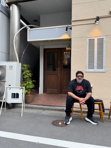 Reviewer wearing the black Statement Made California t-shirt while sitting outside a building in Tokyo.