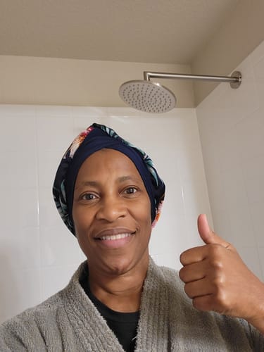 Customer gives a thumbs-up in front of the installed 8 Inch Rain Shower Head in a white tiled shower.