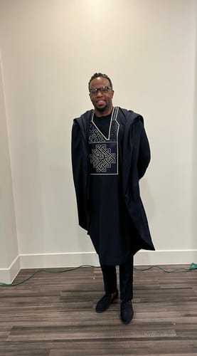 Customer standing in the Purple Amani Signature Agbada, showing the full-length outfit with its intricate embroidery.