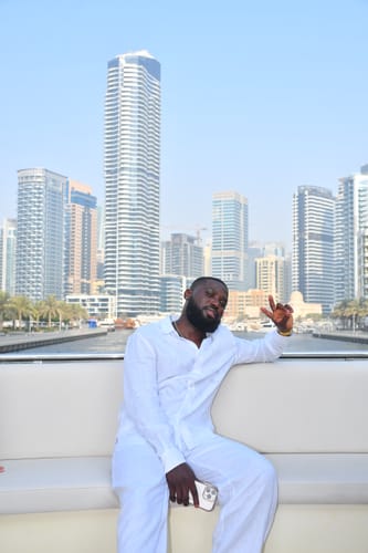 Reviewer relaxing on a boat wearing the comfortable White Linen Set with a city skyline in the background.