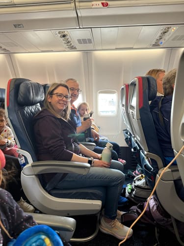 Customer wearing the Deep Plum Ryann Hoodie while seated on an airplane, holding a water bottle.