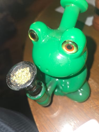 Customer's green Froggy Glass Bong, shown close-up on a wooden surface with a packed herb bowl.