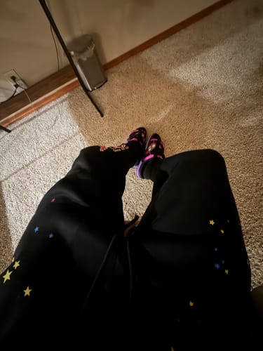 A reviewer's first-person view of their black and colorful Mystery DracoSlides being worn indoors.