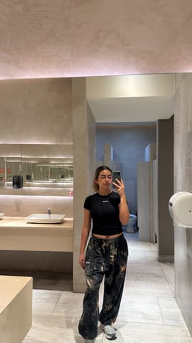 Reviewer in a mirror selfie showing the baggy fit of the Camo Pump Cover Joggers in a restroom.