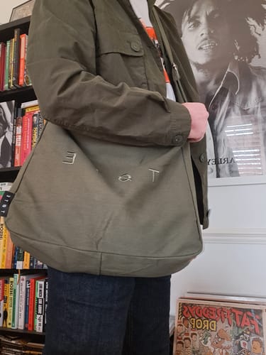 A customer wears the khaki green ALTA crossbody bag over a matching jacket, showcasing its everyday style.