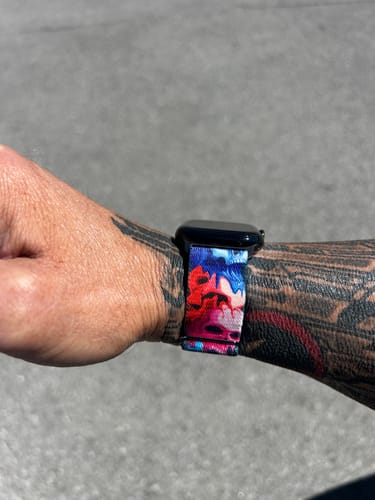 Close-up of a customer wearing the colorful Reflect Watch Band on a tattooed wrist.
