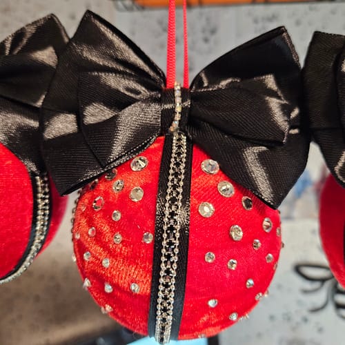 Close-up of a customer's handmade ornament made with the red crushed velvet, decorated with a black bow and rhinestones.