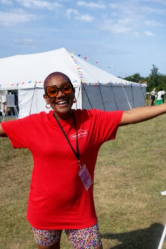 Reviewer smiling while wearing the red Technical t-shirt outdoors at an event.