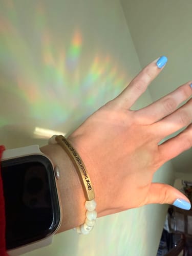 Customer wearing the 'Grow Through What You Go Through' bracelet with white beads and an engraved bar on their wrist.