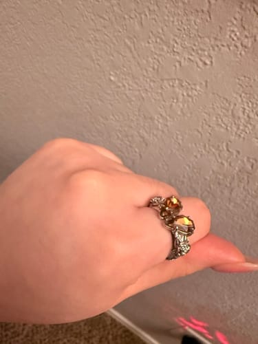 A customer's hand wearing the Promise Ring, showing the two coffin-shaped stones and detailed rose band.