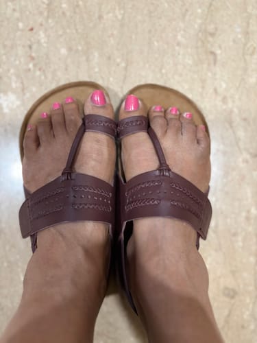 Customer's feet viewed from above, wearing the brown Frido Puneri Chappals with decorative straps.