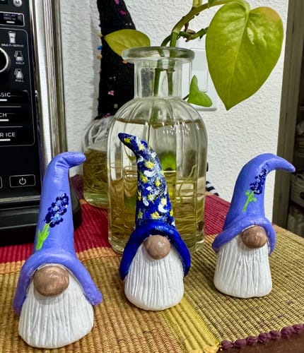 Customer's three hand-painted gnome figurines, a finished project from the creative subscription box, sitting on a table.