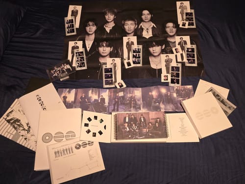 Customer's BTS Arirang album set contents, including a poster and photobooks, spread out on a dark surface.