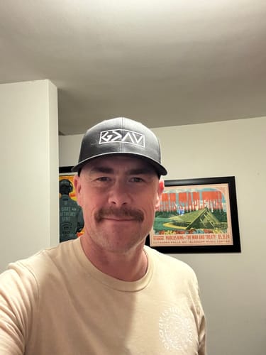 Reviewer wearing the dark gray God is Greater Than the Highs and Lows Richardson Hat indoors.