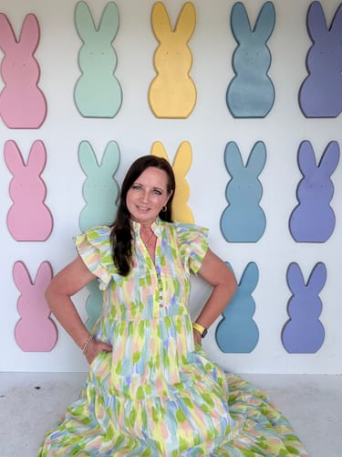 Reviewer sitting in the colorful Brush Stroke Tiered Midi Dress, showing its flowy fit and flutter sleeves.