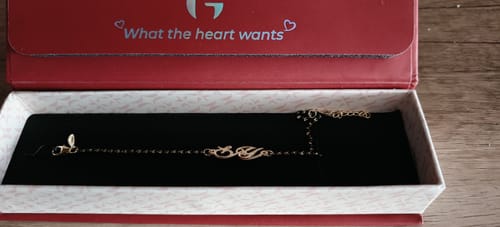 Reviewer's Golden Personalised Mangalsutra Bracelet with an initial charm, presented inside its red and white jewellery box.