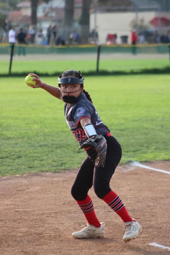 Customer wearing the black Firecrackers NEO Softball Fielder's Mask while throwing a softball on a field.