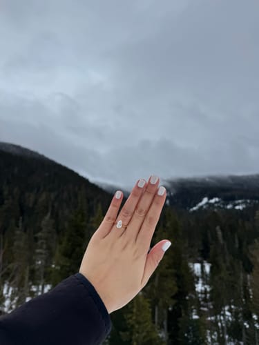 Reviewer's hand wearing the Cathedral Royale pear engagement ring against a snowy mountain background.