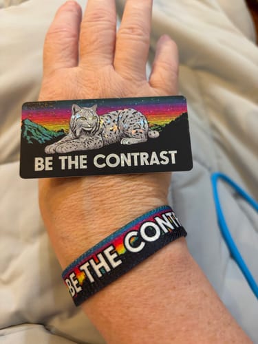 Reviewer wears the 'Be The Contrast' wristband and holds the matching card with a lynx illustration.
