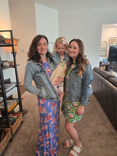 Two reviewers wearing green and blue versions of the Whimsical Floral Knit Tank Dress with denim jackets indoors.