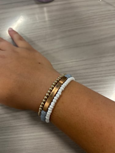 Reviewer's wrist wearing the SURVIVOR bracelet stacked with two other beaded bracelets.