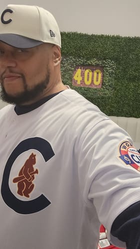 Customer in a custom white baseball jersey, showing a close-up of the chest logo and sleeve patch.