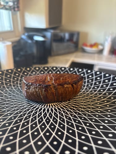 Customer's thick, cooked Beef Tenderloin Steak served on a patterned black and white plate.